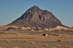 a large mountain in the distance with a small house on it