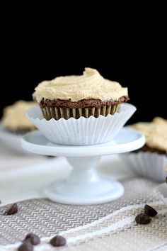 two cupcakes with frosting and chocolate chips on a white cake platter