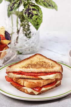 a toasted sandwich on a plate next to a vase with flowers