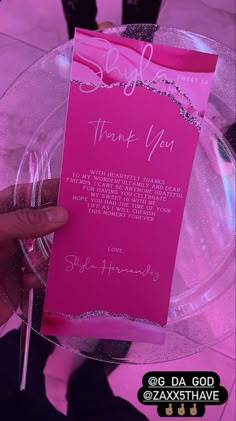 a person holding up a pink thank you card on a clear plate with silver trim