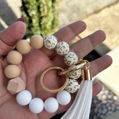 a person holding several different types of beads in their palm hand, one with a tassel and the other with a keychain