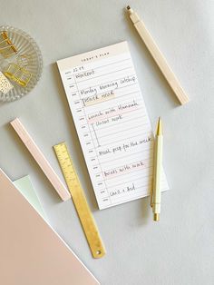 a notepad, pen, ruler and other office supplies on a table with paper