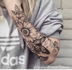 a woman's arm with sunflowers and butterflies tattooed on the arm,