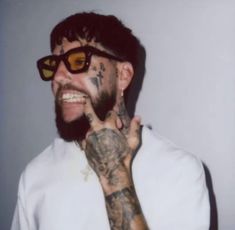 a man with tattoos and sunglasses making the peace sign