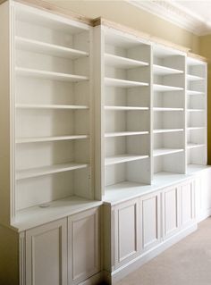 two white bookshelves in the middle of a room with carpeted flooring