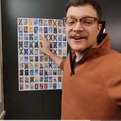 a man in an orange hoodie is pointing at some stickers on the wall