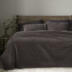 a bed with a brown comforter and pillows in a room next to a wooden headboard