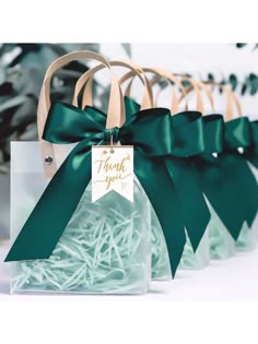 small clear gift bags with green bows and thank you tags on them for wedding favors