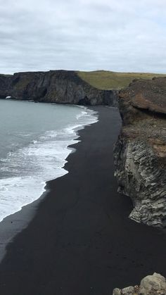 black sand beach with cliffs and ocean in the background