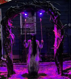 a woman with long hair standing in front of a purple lit arch and holding a stick