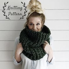 a woman wearing a green knitted scarf with a knot around her neck, standing in front of a white wall