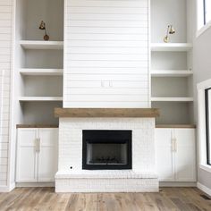 an empty living room with white bookcases and a fireplace