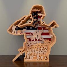 a wooden cutout of the united states with an american flag in the center and silhouettes of people on it