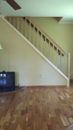 a living room with hard wood flooring and a tv on the far side of the wall