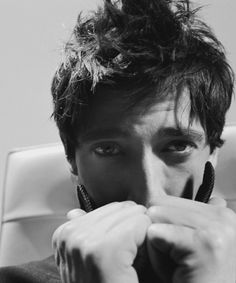 black and white photograph of a man covering his face with his hands while sitting in a chair