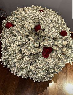 a bunch of money sitting on top of a wooden floor next to a red rose