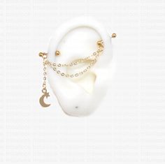 a pair of ear rings with chains and moon charms hanging from the end of them