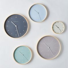 four clocks with different colors are arranged on a white surface, one is blue and the other is grey