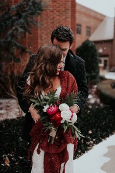 a man and woman standing next to each other in front of a building with snow on the ground