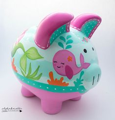 a pink and blue piggy bank sitting on top of a white table