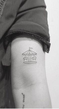 a person with a tattoo on their arm that has an image of a carousel ride