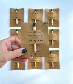 a hand holding a small wooden toothbrush in front of a bunch of tags with writing on them