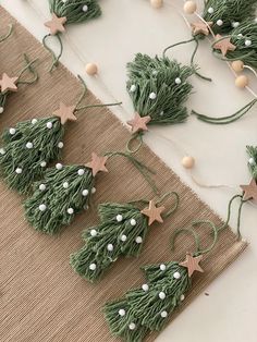 green christmas tree decorations on a table with white balls and twine stars hanging from them