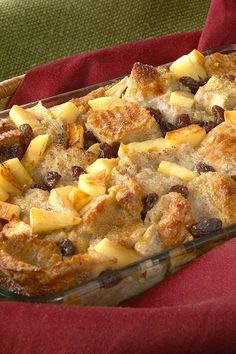 a casserole dish with apples and raisins in it on a red cloth