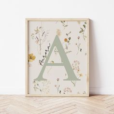 the letter a is surrounded by wildflowers and daisies on a white wall