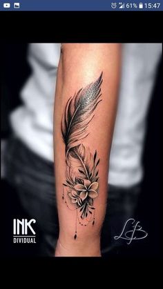 a black and white photo of a feather with flowers on the arm, done by tattoo artist