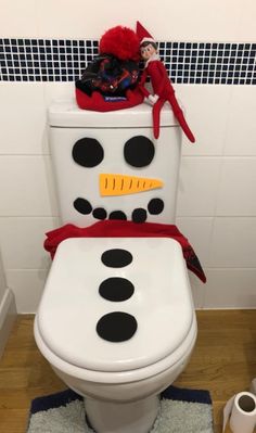 the elf is sitting on top of the toilet in the bathroom with snowman decorations