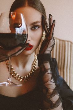 a woman sitting on a couch with a glass of wine in front of her face