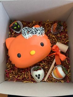 an orange hello kitty cake in a box with candy and candies on the side