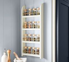 a wall mounted spice rack in the corner of a kitchen