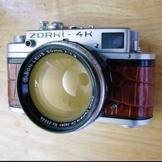 an old fashioned camera sitting on top of a wooden table