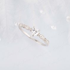 a diamond ring on top of a white background with feathers in the air behind it