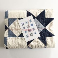 a piece of quilted material tied to a white wall with blue and grey stars on it