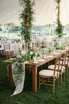 a long table with white flowers and greenery is set up for an outdoor reception