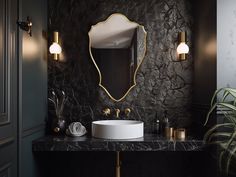 a bathroom with black marble counter top and gold accents on the mirror above the sink