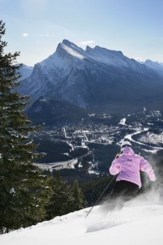 a person on skis going down a snowy hill with mountains in the back ground