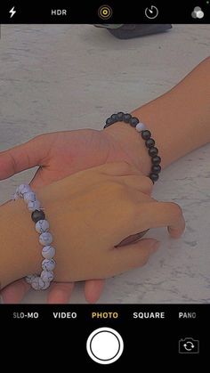 two hands with bracelets on each hand, one holding the other's wrist