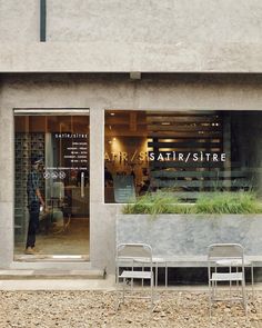 two chairs sitting in front of a store window with plants on the windows sill