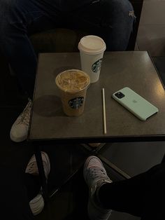 a person sitting at a table with a cup of coffee and cell phone on it