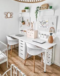 a white desk with two chairs and a laptop on it in front of a wicker basket