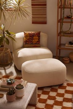 a white chair and ottoman in a room with potted plants on the side table