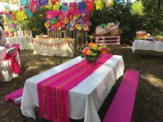 a table set up for a party with colorful decorations on the tables and chairs around it