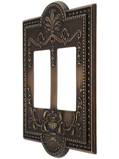 an ornate double light switch plate cover in antique brass finish, with two decorative designs