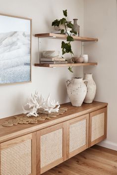 a wooden shelf with vases and other items on top of it in a living room