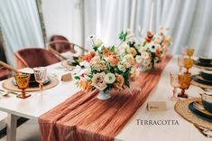 the table is set with orange and white flowers