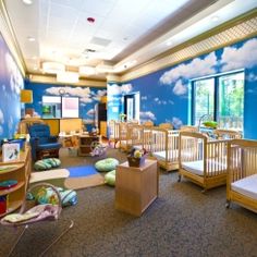 a child's room with blue walls and clouds painted on the wall behind cribs